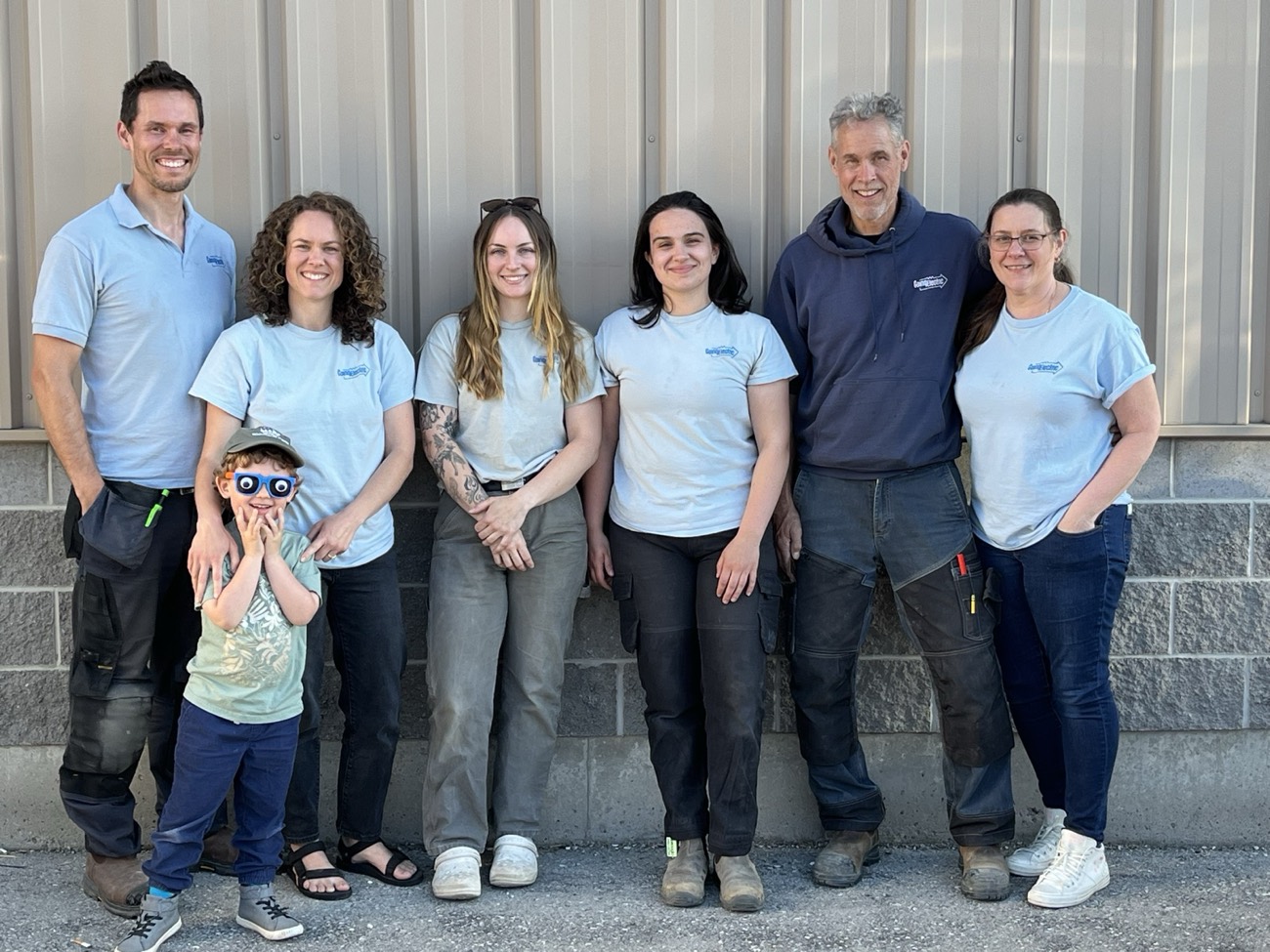 The Going Electric team: electricians and apprentices, with a young family member, outside the shop